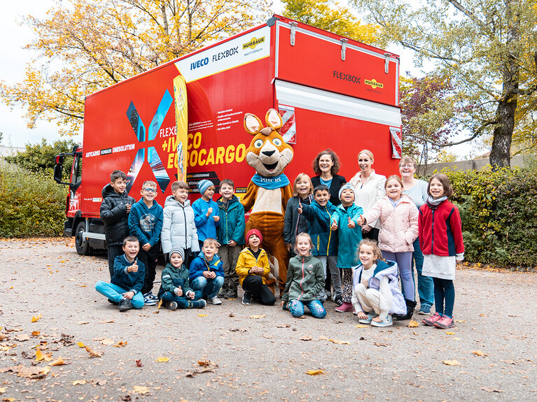 Mascot Blicki together with children in front of a red lorry | © Humbaur GmbH